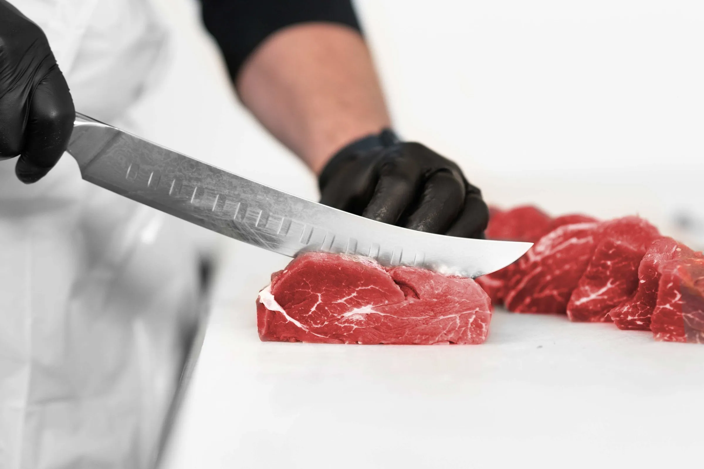 A butcher trimming a fresh beef cut